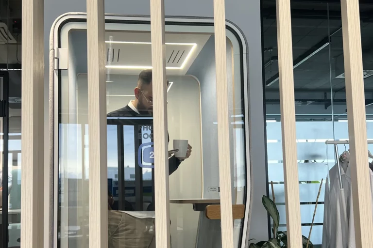 Telefonbox auf der Coworking-Fläche im DC Tower 3 in Wien, darin ein Mann mit Kaffeetasse am Handy